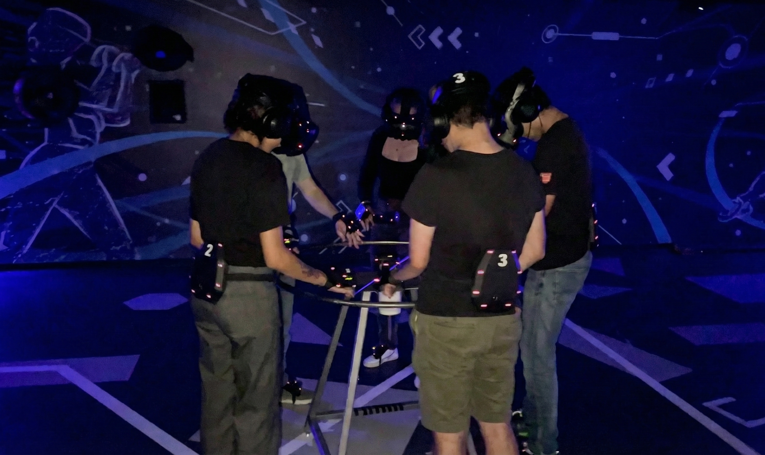 Team Building Activities in Dubai 2 A squad of five in headsets and tracking gear standing in the VR Point free-roam arena before a co-op mission
