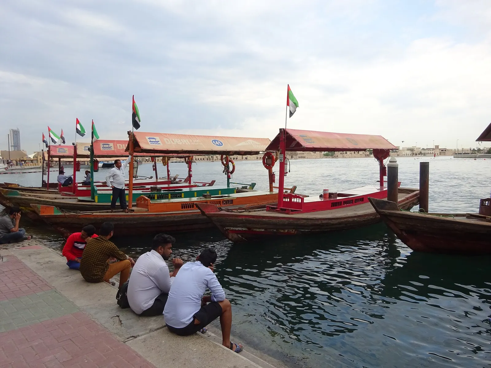 The Best Day in Dubai: A One-Day Itinerary With Every Dirham Counted 8 Wooden abra boats with UAE flags moored on Dubai Creek